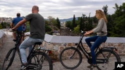Arhiva - Turisti na biciklima iznad pruge podzemne železnice u Tisionu, Grčka, 21. septembra 2022.