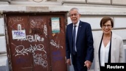 Austrian President Alexander Van der Bellen walks outside the polling station with his wife Doris Schmidauer during presidential elections in Vienna, Austria, Oct. 9, 2022. 