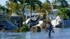 Seorang warga berjalan di lingkungan tempat tinggalnya yang tergenang banjir setelah Badai Ian melanda daerah Fort Myers, Florida, pada 29 September 2022. (Foto: AP/Steve Helber)