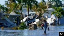 Seorang warga berjalan di lingkungan tempat tinggalnya yang tergenang banjir setelah Badai Ian melanda daerah Fort Myers, Florida, pada 29 September 2022. (Foto: AP/Steve Helber)