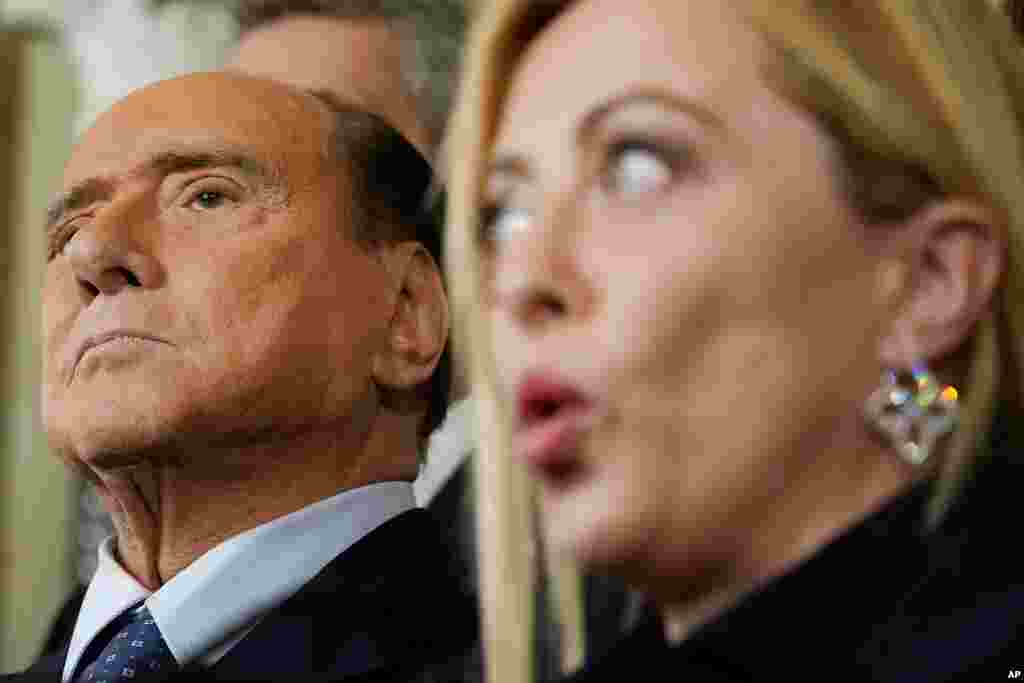 Forza Italia leader Silvio Berlusconi, left, listens to Brothers of Italy&#39;s leader Giorgia Meloni talking to journalists at the Quirinale Presidential Palace after a meeting with Italian President Sergio Mattarella as part of a round of consultations with party leaders to try and form a new government, in Rome.