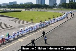 Aksi pembentangan spanduk sepanjang 220 meter di pelataran Monas, Jakarta, suarakan pentingnya aksi nyata atasi ancaman krisis iklim dan kemiskinan pada anak, Sabtu (29/10). (Foto: Save the Children Indonesia)