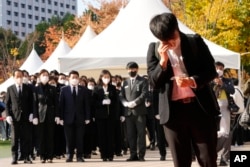 A mourner wipes his tear as he pays a silent tribute for victims of a deadly accident following Saturday night's Halloween festivities, at a joint memorial altar for victims at Seoul Square in Seoul, South Korea, Monday, Oct. 31, 2022. (AP Photo/Ahn Young