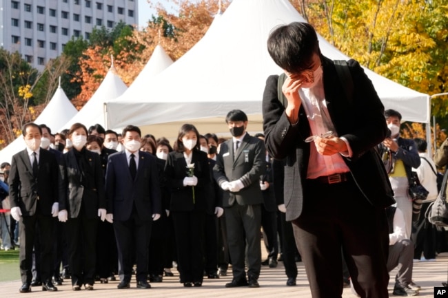 A mourner wipes his tear as he pays a silent tribute for victims of a deadly accident following Saturday night's Halloween festivities, at a joint memorial altar for victims at Seoul Square in Seoul, South Korea, Monday, Oct. 31, 2022. (AP Photo/Ahn Young