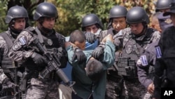 Fuerzas Especiales de la Policía Nacional Civil trasladan a hombres detenidos por sus posibles vínculos con pandillas en Comasagua, El Salvador, el lunes 3 de octubre de 2022. (Foto AP/Salvador Meléndez)