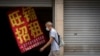 一名男子走过北京街头一家招租的商铺。（2022年8月17日）
