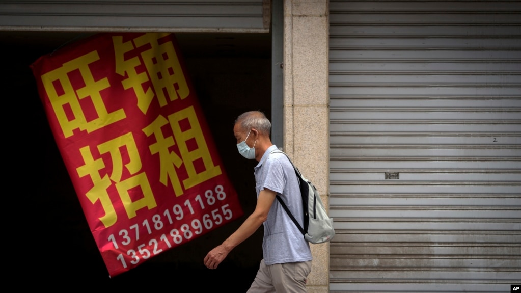 一名男子走过北京街头一家招租的商铺。（2022年8月17日）