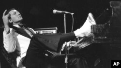 FILE - Jerry Lee Lewis props his foot on the piano as he acknowledges fans' applause during the fifth annual Rock 'n' Roll Revival at New York's Madison Square Garden on March 14, 1975.