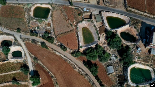 Инновационные искусственные пруды видны между сельскохозяйственными полями в деревне Харф-Бейт-Хасна, провинция Динние, север Ливана, 7 сентября 2022 года.