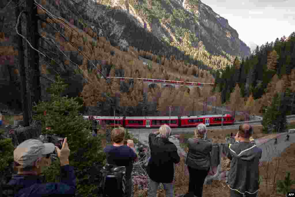Members of the public take photos of a 1910-metre-long train with 100 cars passing near Bergun, Oct. 29, 2022, during a record attempt by the Rhaetian Railway (RhB) of the World&#39;s longest passenger train, to mark the Swiss railway operator&#39;s 175th anniversary.