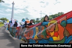 Aksi pembentangan spanduk sepanjang 220 meter di pelataran Monas, Jakarta, suarakan pentingnya aksi nyata atasi ancaman krisis iklim dan kemiskinan pada anak, Sabtu (29/10). (Foto: Save the Children Indonesia).