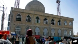 塔利班一名战斗人员在遭炸弹攻击的一座清真寺前面站岗（2022年4月21日）