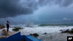 Hurricane Ian became a major hurricane as it neared a landfall over western Cuba. Hours before it did, a woman took photos as Ian passed through George Town, Grand Cayman island, Monday, Sept. 26, 2022. 