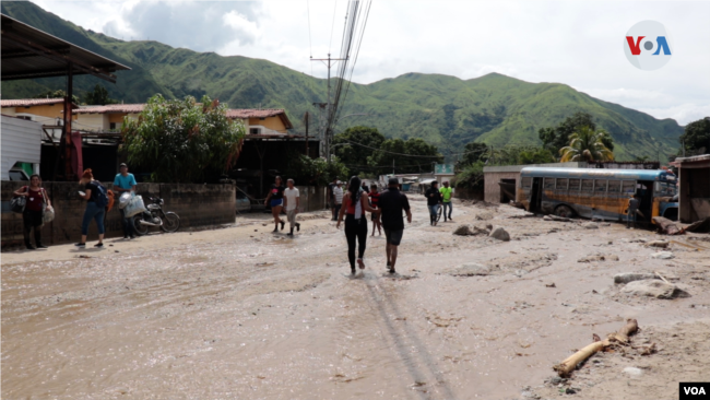 Entre lodo y agua vecinos de Maracay, Venezuela, intentan recuperar lo que queda tras aluvión