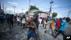 A protester carries a piece of wood simulating a weapon during a protest demanding the resignation of Prime Minister Ariel Henry, in the Petion-Ville area of Port-au-Prince, Haiti, Oct. 3, 2022. 
