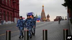 Policemen walk at Red Square with the St. Basil's Cathedral and Lenin Mausoleum in the background ahead of a planned concert in Moscow, Sept. 29, 2022.