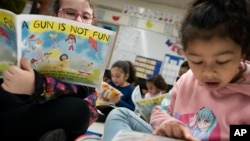 Children read a book reading on urban gun violence prevention at the Drexel Avenue School, Monday, Oct. 3, 2022, in Westbury, N.Y. (AP Photo/John Minchillo)