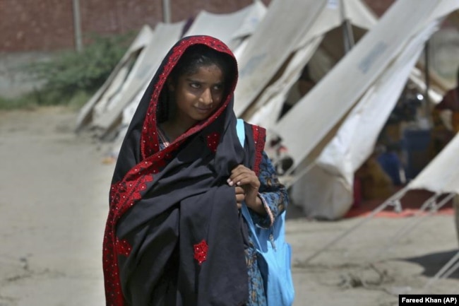 Flood victim Rajul Noor walks towards her tent school at a relief camp, in Dadu district, Pakistan, Sept. 23, 2022. (AP Photo/Fareed Khan)