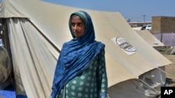 Shakeela Bibi who is pregnant stands beside her tent at a relief camp for flood victims, in Fazilpur near Multan, Pakistan, Sept. 23, 2022.