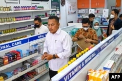 Polisi mengunjungi toko obat di Banda Aceh, untuk memeriksa formula sirup untuk anak-anak, menyusul meningkatnya kematian anak akibat cedera ginjal, 24 Oktober 2022. (CHAIDEER MAHYUDDIN / AFP)