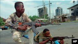 FILE - Fighters from the United Liberation Movement of Liberia (ULIMO) shoot their way through downtown Monrovia, LIberia, April 16, 1996. Trial started Oct. 10, 2022, in Paris for a former Liberian rebel accused of crimes against humanity.