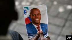 ARCHIVO - Una persona sostiene una fotografía del fallecido presidente haitiano Jovenel Moïse durante su ceremonia conmemorativa en el Museo Nacional del Panteón en Puerto Príncipe, Haití, el 20 de julio de 2021.