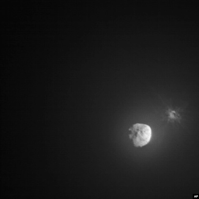 In this image made available by NASA, debris ejects from the asteroid Dimorphos, right, a few minutes after the intentional collision of NASA’s Double Asteroid Redirection Test (DART) mission on Sept. 26, 2022, captured by the nearby Italian Space Agency’