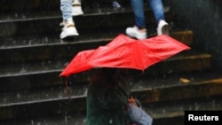 ARCHIVO - Una persona se protege de la lluvia causada por el potencial ciclón tropical dos, a su paso por el Caribe, en Caracas, Venezuela, el 29 de junio de 2022. REUTERS/Leonardo Fernández Viloria