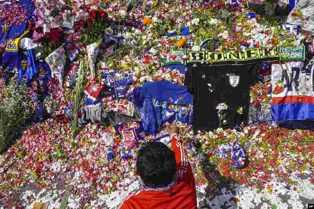 A man throws flowers outside Kanjuruhan Stadium where a soccer stampede killed more than 100 people, in Malang, East Java, Indonesia. An Indonesian police chief and nine elite officers were removed from their posts and 18 others were being investigated for responsibility in the firing of tear gas inside a soccer stadium that set off a stampede, officials said.