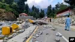 FILE - Local residents walk in the road destroyed by floodwaters in Kalam Valley in northern Pakistan, Sept. 4, 2022.