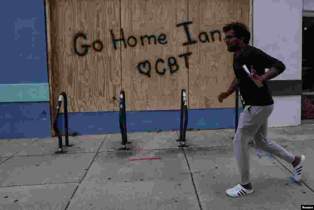 A man runs by a boarded-up storefront in Tampa, Florida, Sept. 27, 2022, as Hurricane Ian spins toward the state carrying high winds, torrential rains and a powerful storm surge.