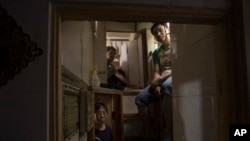 FILE - Hong Kong residents pose at their shoebox apartments in Hong Kong, May 4, 2017.