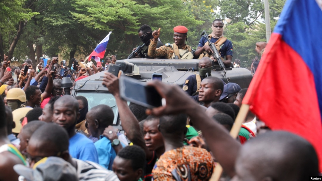 Burkina Faso's self-declared new leader Ibrahim Traore is welcomed by supporters holding Russian's flags as he arrives at the national television standing in an armored vehicle in Ouagadougou, Oct. 2, 2022.