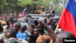 Burkina Faso's self-declared new leader Ibrahim Traore is welcomed by supporters holding Russian's flags as he arrives at the national television standing in an armored vehicle in Ouagadougou, Oct. 2, 2022.