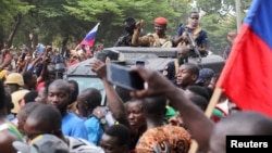 Burkina Faso's self-declared new leader Ibrahim Traore is welcomed by supporters holding Russian's flags as he arrives at the national television standing in an armoured vehicle in Ouagadougou, Oct. 2, 2022.