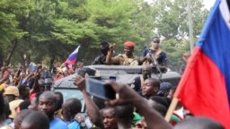 Burkina Faso's self-declared new leader Ibrahim Traore is welcomed by supporters holding Russian's flags as he arrives at the national television standing in an armoured vehicle in Ouagadougou, Oct. 2, 2022.