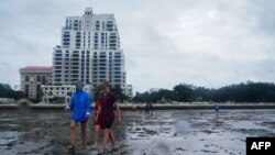 Sejumlah warga tampak berjalan di atas lumpur di area Tampa Bay, Florida, menjelang datangnya badai Ian ke wilayah tersebut pada 28 September 2022. (Foto: AFP/Bryan R. Smith)