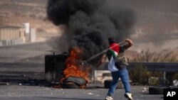 A Palestinian protester uses a slingshot during clashes with Israeli army troops in the West Bank city of Ramallah, Oct. 20, 2022. 