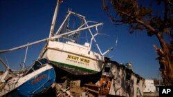 A boat lies grounded against the second story of an apartment building, now missing its first story, on San Carlos Island in Fort Myers Beach, Fla., Oct. 7, 2022. 