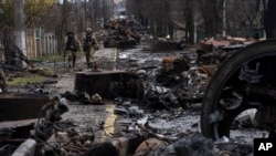 FILE - Ukrainian soldiers walk amid destroyed Russian tanks in Bucha, on the outskirts of Kyiv, Ukraine, April 3, 2022. 