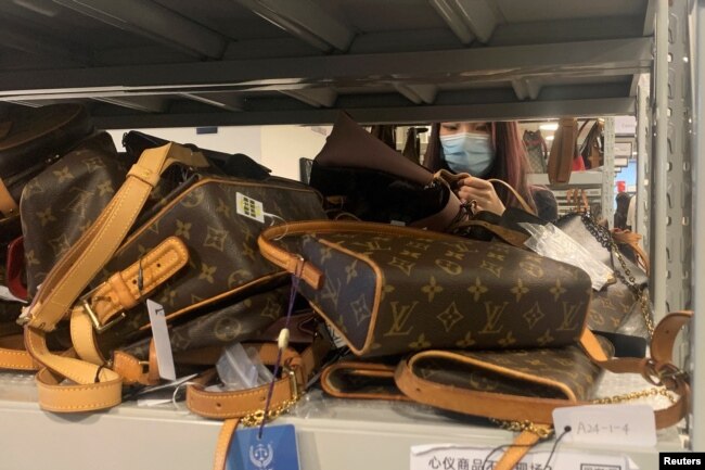 A customer looks at bags displayed at a store of second-hand luxury goods platform ZZER in Shanghai, China September 9, 2022. (REUTERS/Xihao Jiang)