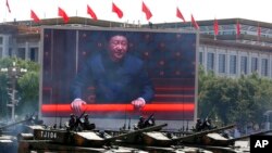 FILE - Chinese President Xi Jinping is displayed on a screen as tanks take part in a parade commemorating the 70th anniversary of Japan's surrender during World War II held in front of Tiananmen Gate in Beijing on Sept. 3, 2015. 