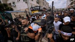 Armed Palestinians carry the body of Mahmoud Al-Sous, covered with a flag of the Islamic Jihad militant group, during his funeral in the West Bank town of Jenin, Oct. 8, 2022.