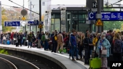 Rail passengers wait for a train on a platform at the main train station in Berlin, Oct. 8, 2022, following major disruptions on the German railway network. 