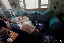FILE - Dirk Russell, who has medical issues, lies on the sofa in his waterlogged home that flooded in the aftermath of Hurricane Ian on Pine Island, Fla., Saturday, Oct. 1, 2022.