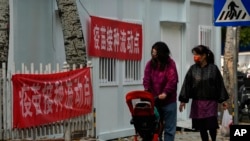 資料照：帶著口罩推著嬰兒車的女子走過北京的一處疫苗接種流動點。 （2022年10月26日）
