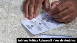 La foto muestra a un venezolano completando una boleta de la consulta popular organizada por la oposición el 12 de diciembre de 2020.