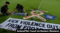 Suporter klub sepak bola memasang atribut klub Arema saat berjaga di Stadion Kapten I Wayan Dipta di Bali pada 3 Oktober 2022, untuk menunjukkan solidaritas terhadap para korban kerusuhan di Stadion Kanjuruhan, Malang. (Foto: Antara/Fikri Yusuf via Reuters)