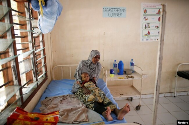 FILE - A Somali refugee holds a toddler at a hospital in the Dadaab refugee camp, Kenya, Dec. 19, 2017.