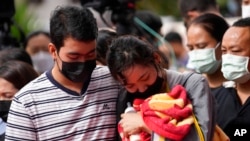 A family of a victim mourns as they bring a blanket and a baby bottle during a ceremony for those killed in the attack on the Young Children's Development Center in Uthai Sawan, Thailand, Oct. 7, 2022.